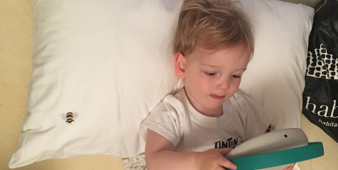 Claire's child reading on a tablet in bed