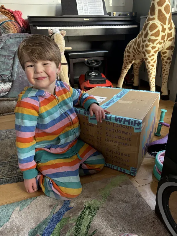 Julia and Vadim's son sitting with a Whirli return box